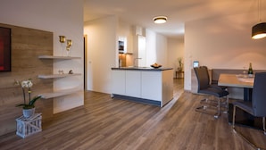 Una cocina moderna con una isla central, armarios blancos y un comedor con mesa y sillas.