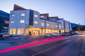 Ein mehrstöckiges Hotel mit moderner Architektur, das eine markante Eingangspartei, einen Parkplatz und einen Blick auf die umliegende Landschaft bietet.