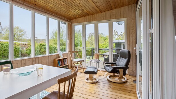 A wooden deck with a table, chairs, and a sofa.
