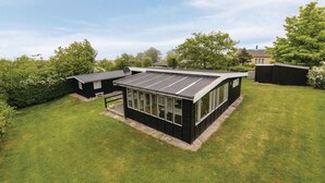 A modern house with a large solar panel roof, a well-maintained lawn, and a small shed.