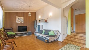 A living room with a sofa, TV, wooden flooring, and a staircase.