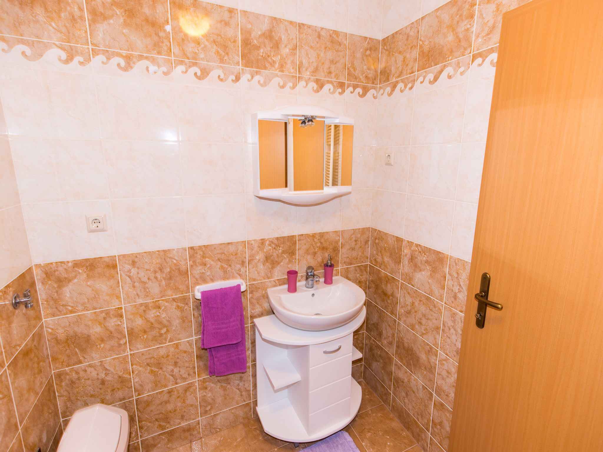 Casa de banho com sanita, lavatório e espelho.