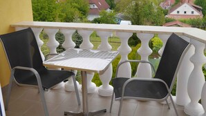 Een balkon met een tafel en twee stoelen, met uitzicht op een landelijk gebied met huizen en groen.