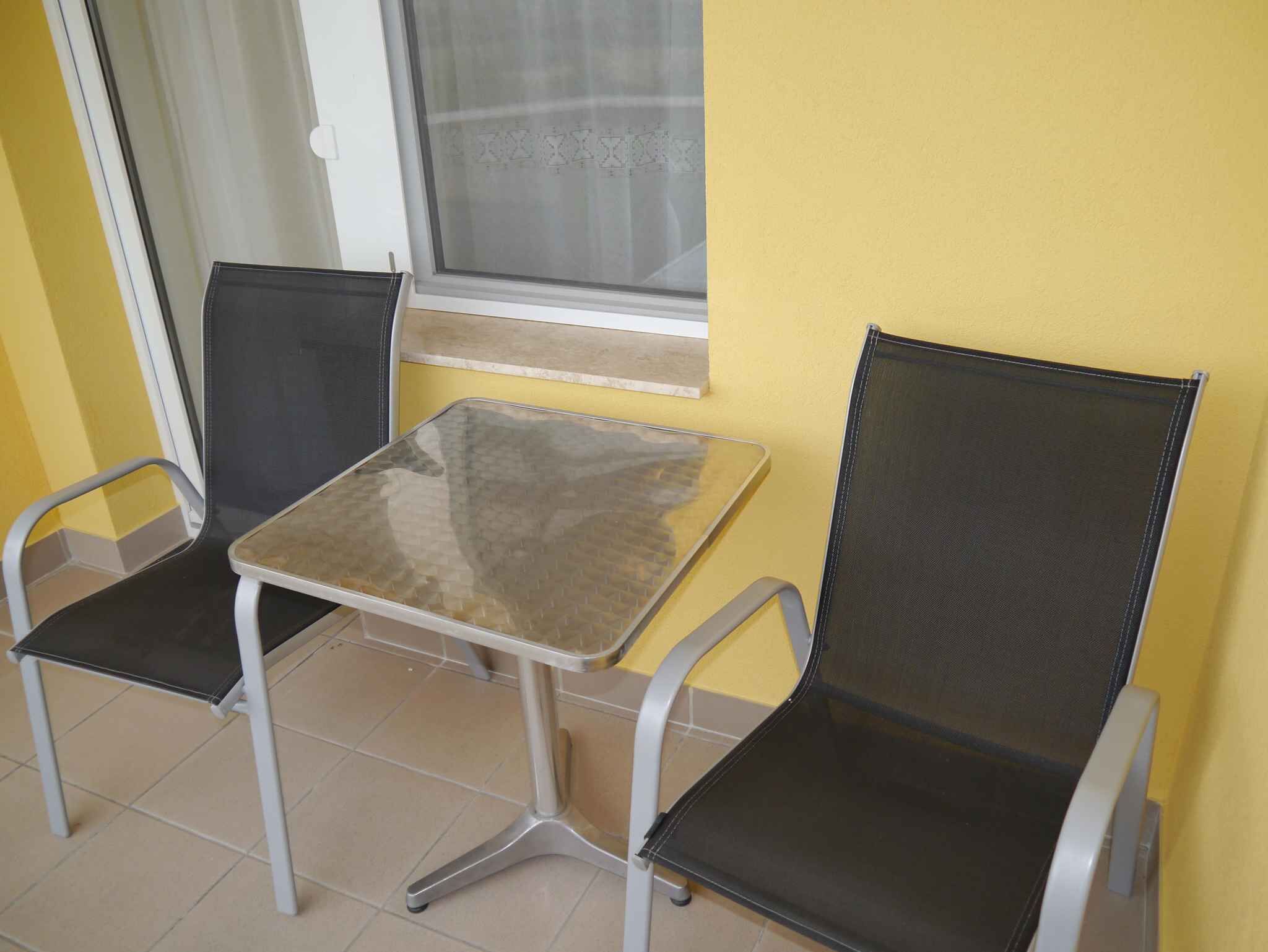 A small balcony with a table and two chairs.