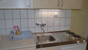 Een keuken met witte kastjes, een roestvrijstalen spoelbak en een ingebouwde oven.