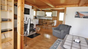 Ein gemütliches Blockhaus-Interieur mit Essbereich, grauem Sofa und Kamin.