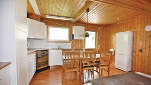 Eine kleine Küche mit Holzwänden, ein Essbereich mit Holzstühlen und ein Kühlschrank.