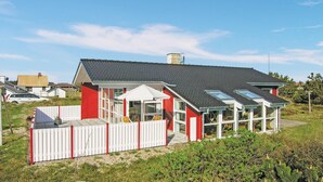 Una casa moderna con tetto spiovente, ampie finestre e un'area esterna recintata.