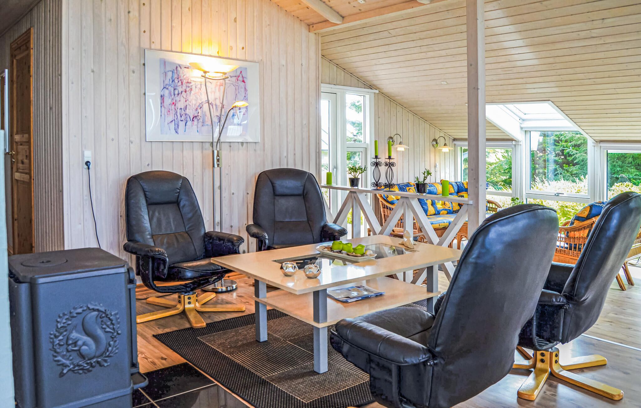 Una sala de reuniones moderna con dos sillones de cuero, una mesa de cristal y un ventanal grande.