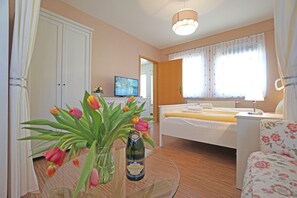 Een kamer met een bed, een televisie, een tafel met bloemen en een stoel.