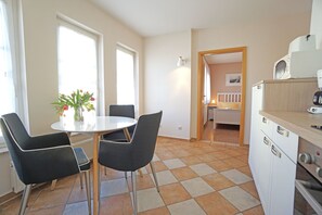 Een keuken met een eettafel, stoelen en een koelkast.