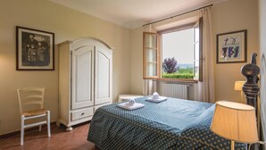 A bedroom with a bed, a chair, a wardrobe, a window with a view, and a lamp. - Cozy home in Cerreto Guidi FI with WiFi (Cerreto Guidi FI)