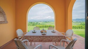 A table set with a tablecloth, chairs, and a view of a green landscape through an archway. - Cozy home in Cerreto Guidi FI with WiFi (Cerreto Guidi FI)