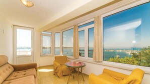 Ein Zimmer mit einem großen Erkerfenster, einem Sofa, einem kleinen runden Tisch und einem Stuhl.