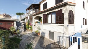 Ein zweistöckiges Haus mit einem Balkon, einer Treppe und Topfpflanzen.