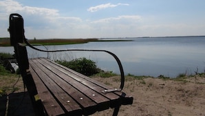 Een houten bank aan een rustig meer met een heldere lucht.