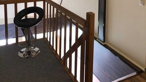 Eine Treppe mit hölzernem Geländer, ein schwarzer Stuhl und ein flachbildfernseher an der Wand.