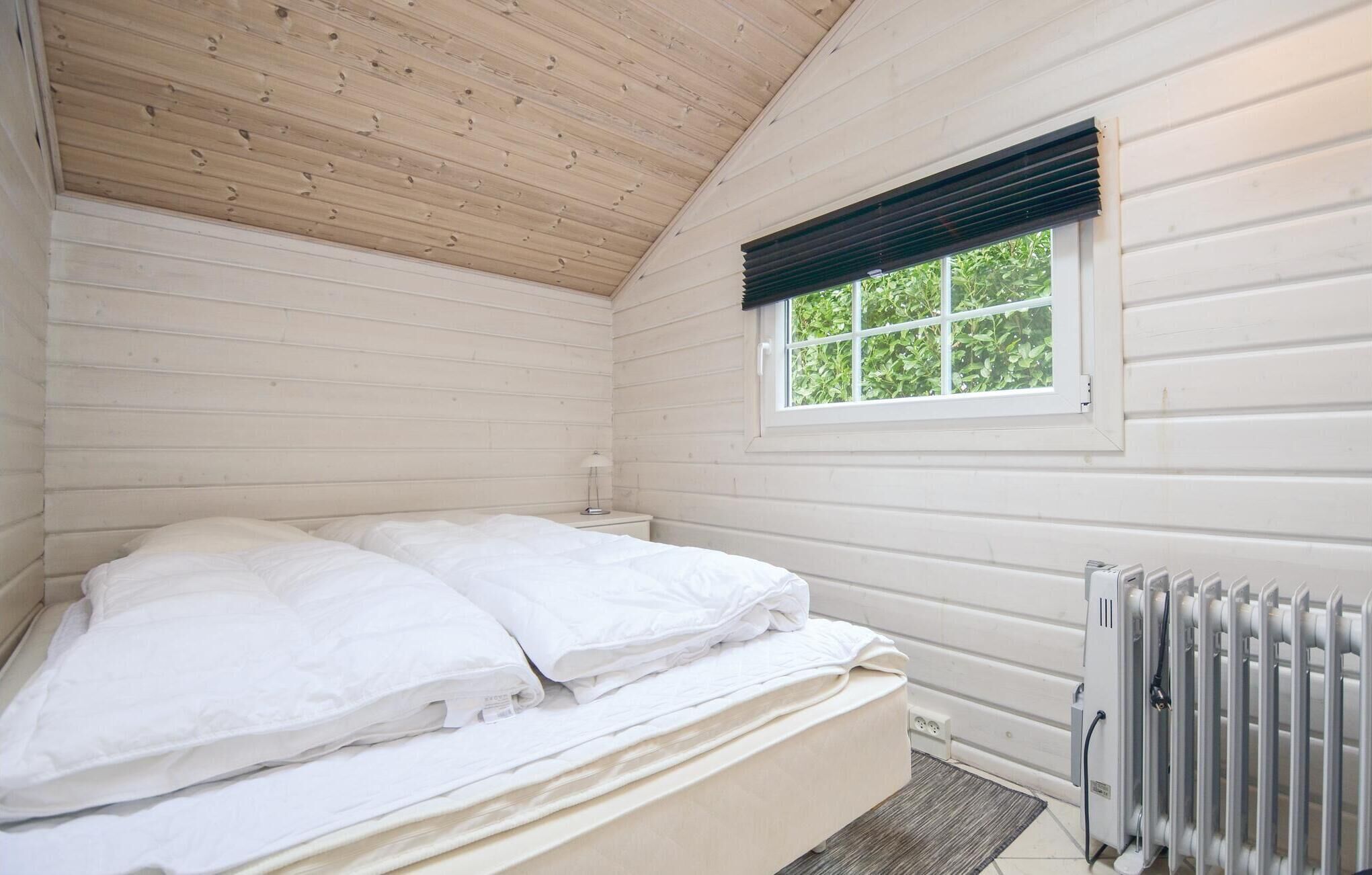 Et soveværelse med seng, et vindue med persienner og en radiator.