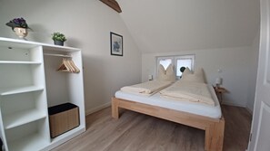 Ein Schlafzimmer mit einem hölzernen Bett, einem weißen Kleiderschrank und einem kleinen Fenster.