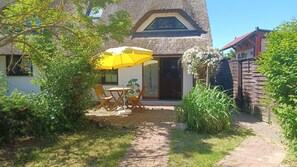 A house with a thatched roof, a paved pathway, and a yellow umbrella.
