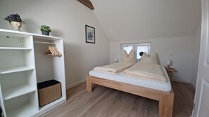 A bedroom with a wooden bed, a white wardrobe, and a small window.