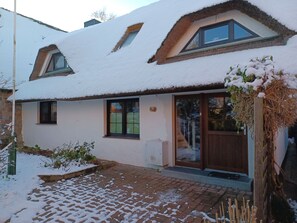 Ein Haus mit verschneietem Dach, einem Ziegelweg und einer Holztür.