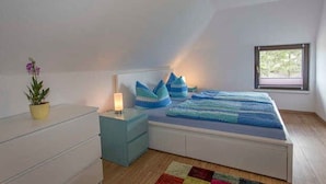 Een slaapkamer met een bed, nachtkastje, lamp en een raam.