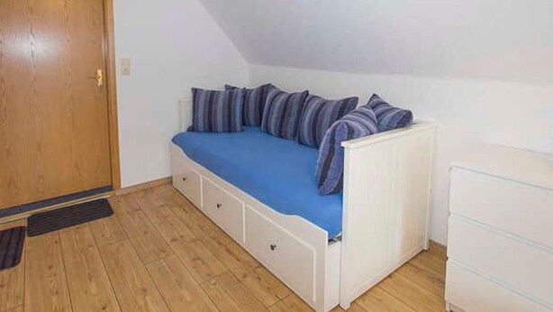 Een kamer met een hoogslaper, een houten deur en een witte ladekast.