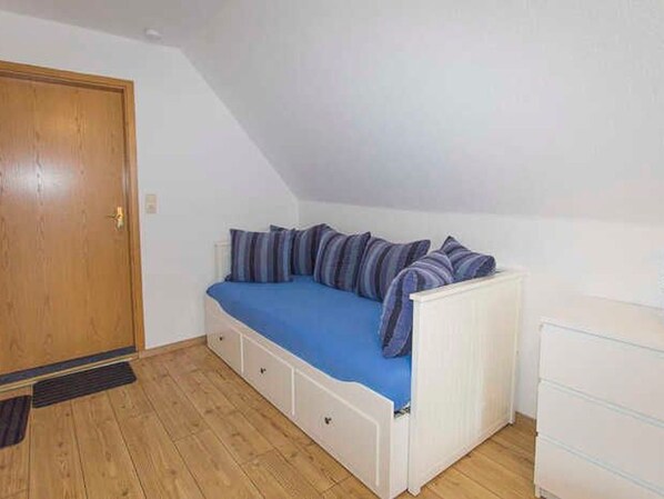 Una habitación con cama tipo litera, una puerta de madera y un aparador blanco.