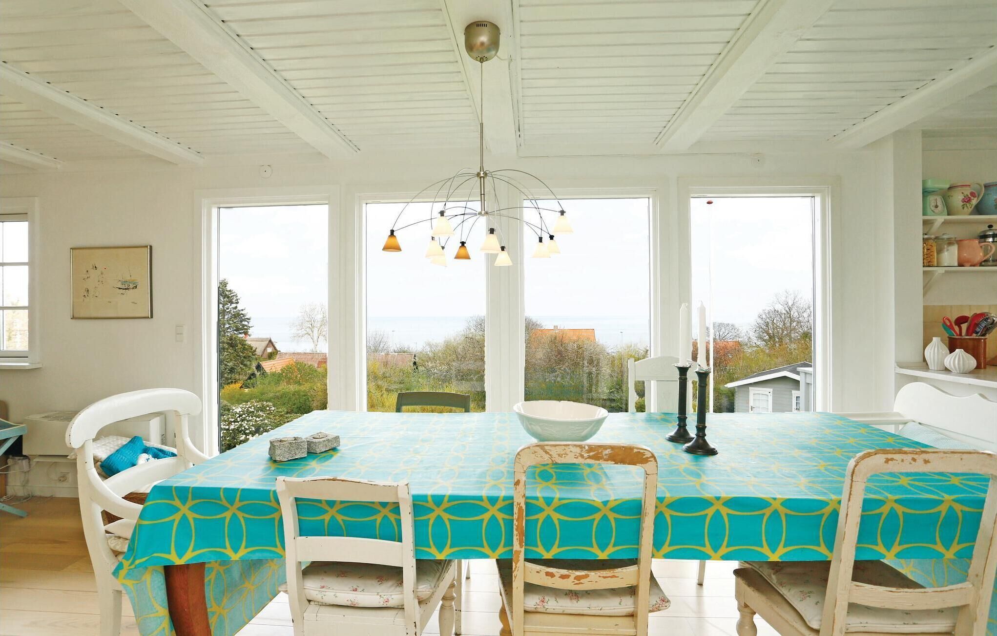 A dining area with a table covered in a blue tablecloth, white chairs, and a chandelier.