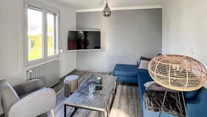 A modern living room with a sofa, armchair, coffee table, and a television mounted on the wall.