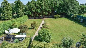 A well-maintained backyard with a lawn, a gravel path, and a picnic area with a table and chairs.