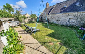 A stone house with a garden, outdoor seating, and a swing set. - 3 bedroom amazing home in Riantec (Riantec)