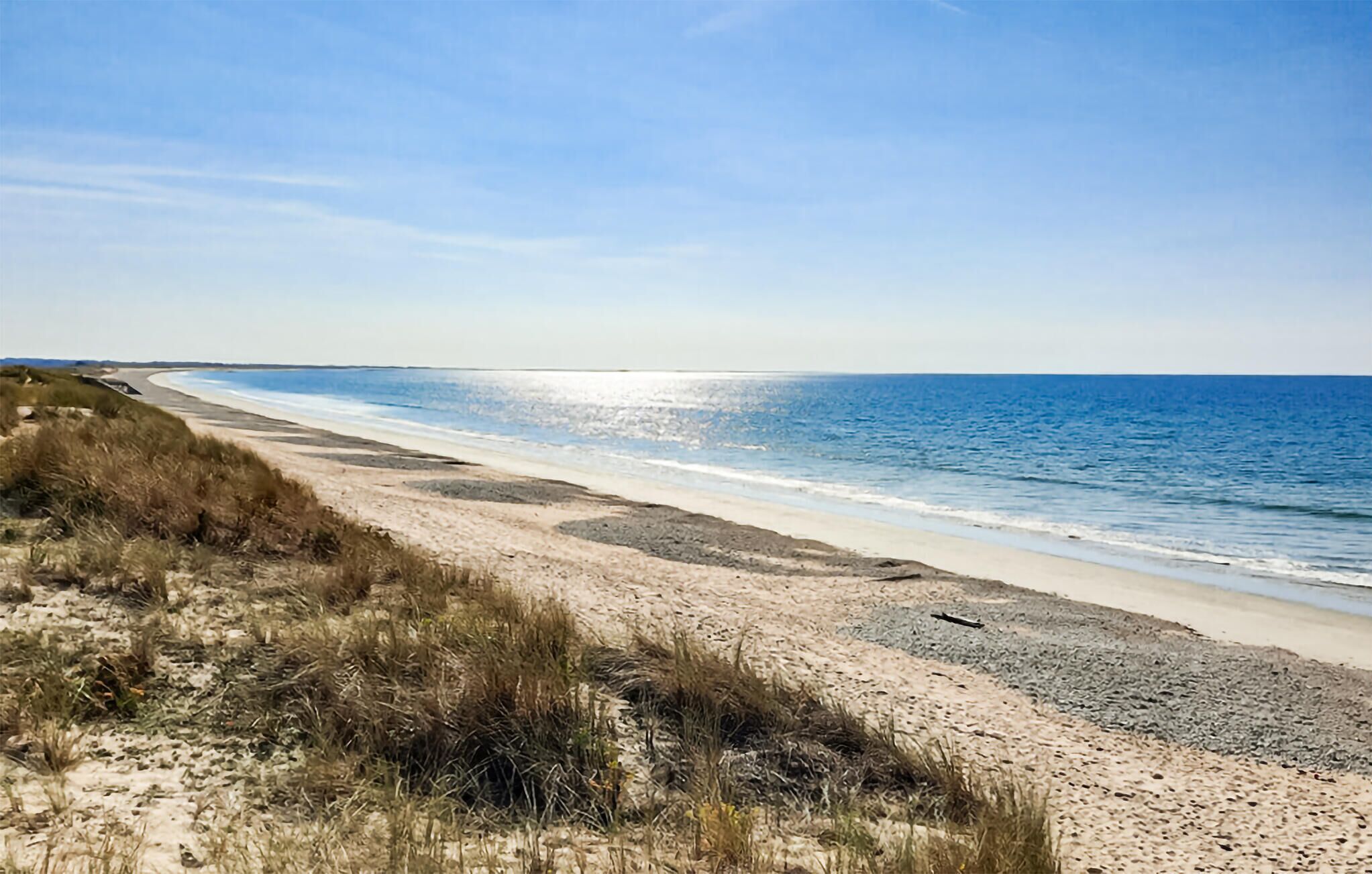 Ein Strand mit blauem Himmel und ruhiger See.