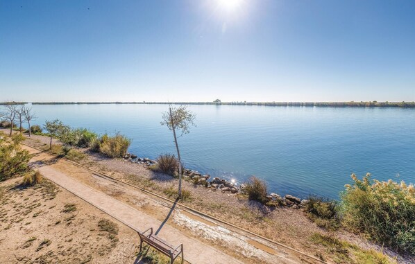 A clear view of a lake with a sandy path and a bench. - Nice apartment in Riumar-Deltebre with swimming pool (Riumar-Deltebre)