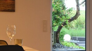 Un interior moderno con comedor y puerta de vidrio que da a un jardín exterior.