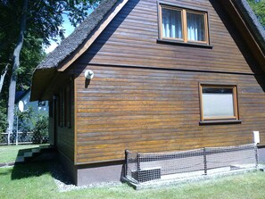 A wooden house with a sloped roof, a window with a shutter, and a small porch area.