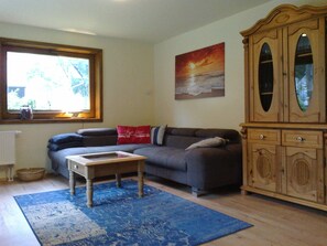 Un salon avec un canapé, une table basse, un meuble et un tableau accroché au mur.
