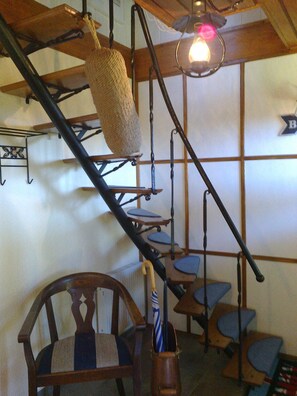 A staircase with a hanging basket, a chair, and a lamp.