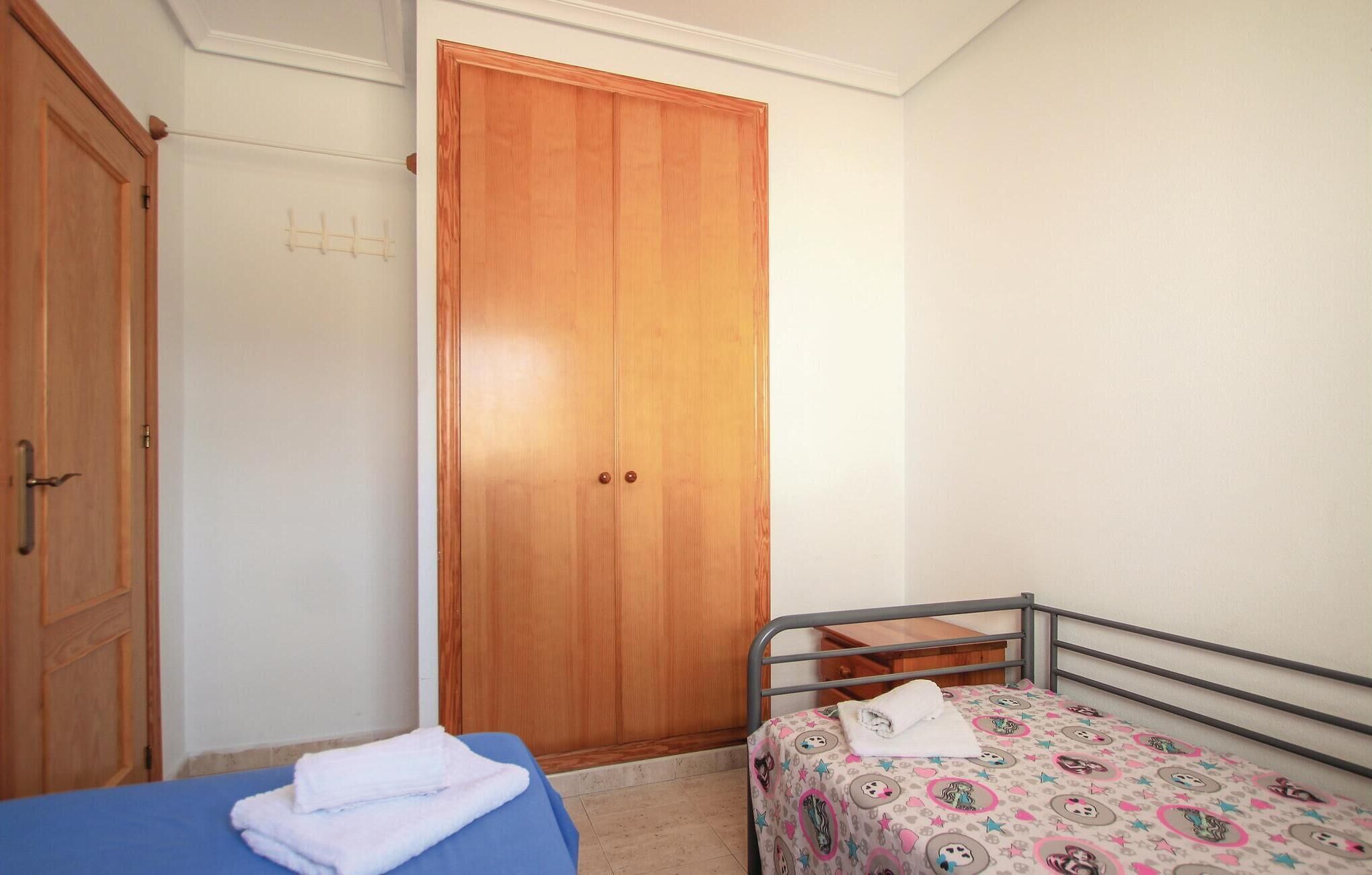 A bedroom with a single bed, a wardrobe, and a bathroom door.