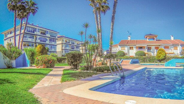 Um resort com piscina, palmeiras e gramado bem cuidado.