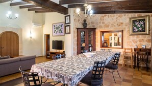 A spacious living area with a long dining table, a sofa, and a television. - Awesome home in Sineu (Sineu)