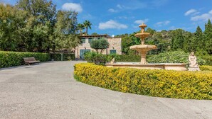 A paved pathway leading to a stone building with a fountain and statue, surrounded by well-maintained hedges and trees. - Awesome home in Sineu (Sineu)