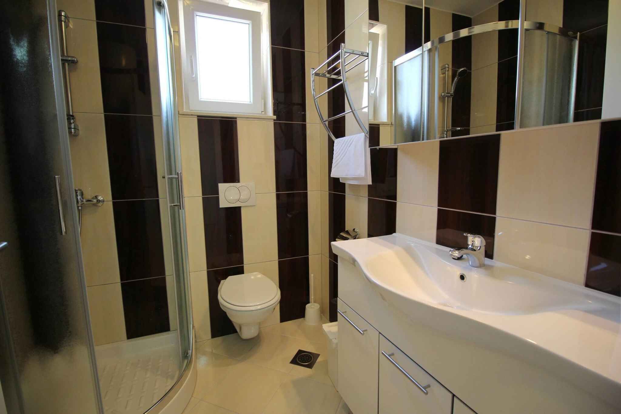 A modern bathroom with a glass shower enclosure, a white sink, and a toilet.