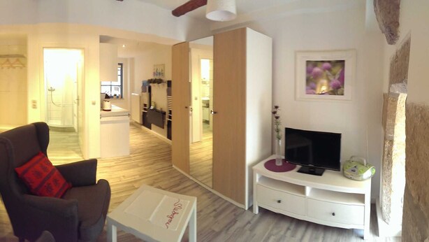 Una sala de estar acogedora con un sofá, sillones, un televisor y un comedor.