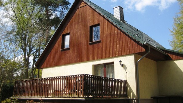 A wooden house with a balcony, a chimney, and a window. - Apartment Zum Kölpinsee - K��lp - Will (Loddin)