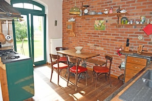 Een keuken met een bakstenen muur, houten kastjes en een eettafel met stoelen.
