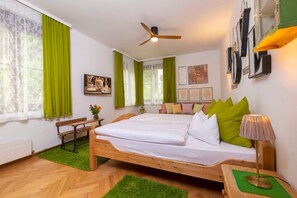 A bedroom with a bed, a desk, a chair, a lamp, and a ceiling fan.