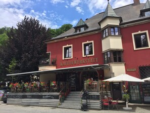 Un bâtiment sur lequel on peut lire l’inscription « KAFFEEWERKSTATT », avec une terrasse aménagée avec des tables et des chaises.