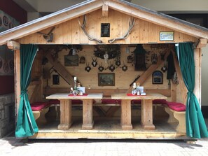 Eine Holzhütte mit Satteldach, einem Tisch mit Kerze und Geweihen an den Wänden.